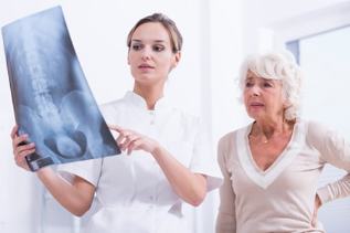 der Arzt zeigt Patientin eine röntgenaufnahme der Wirbelsäule